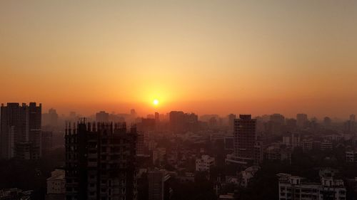 Modern buildings in city against clear sky during sunset