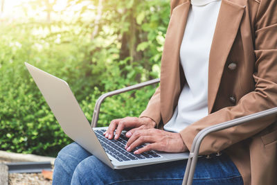 Midsection of businesswoman working on laptop while sitting outdoors