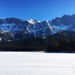Scenic view of mountains against blue sky during winter