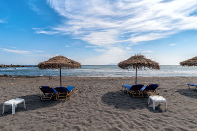 Chairs on beach by sea against sky