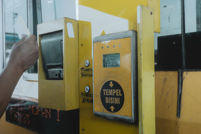 Close-up of hand on yellow telephone