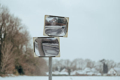 Street mirror in front of trees in winter