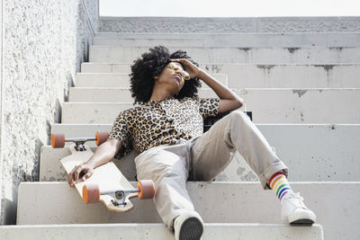 Young afro surfer sitting on some stairs
