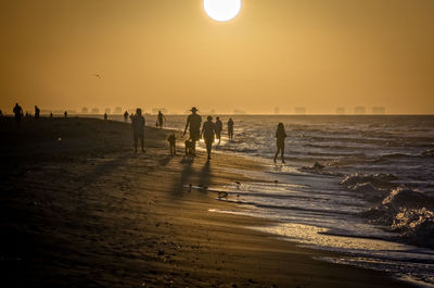 Silhouette people on beach against clear sky during sunset