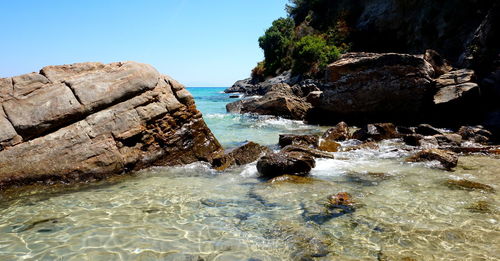 Rock formation on beach against sky