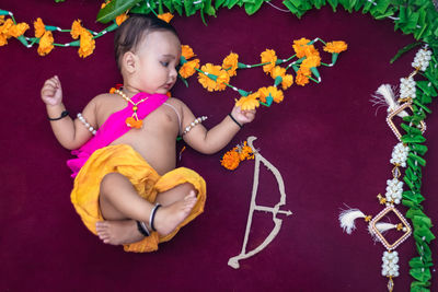 Cute indian boy dresses as lord rama with bow and flowers from top angle