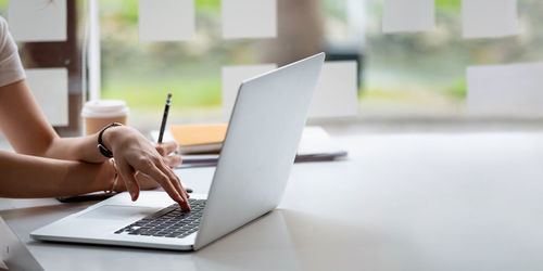 Midsection of man using laptop on table