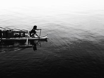 Man rowing boat in sea against sky