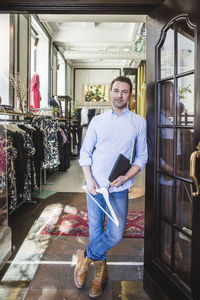 Full length portrait of confident entrepreneur standing on doorway in boutique