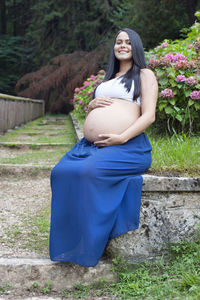 Young pregnant brazilian woman touching her belly in a garden person