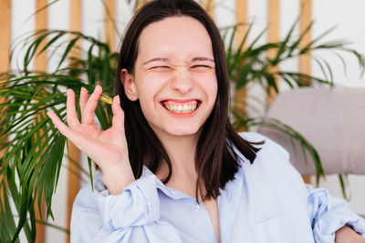 Smiling young woman with short hair holding pill omega capsule in hand at home. girl taking medicine