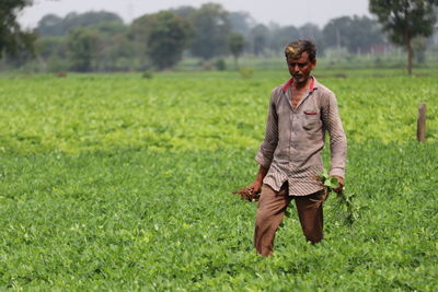 Full length of man walking on field in his hand plants.