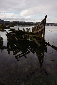 Abandoned boat moored in lake against sky