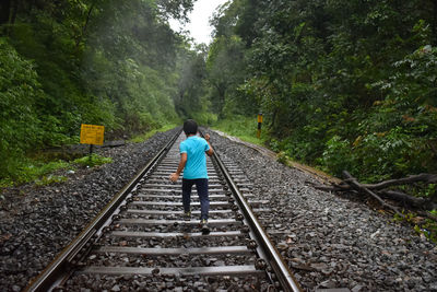 Rear view of boy walking on railroad track