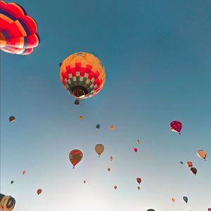 Low angle view of balloons flying against clear blue sky