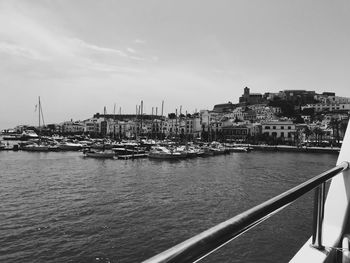 Sailboats moored in sea against buildings in city