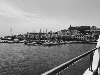 Sailboats moored in sea against buildings in city