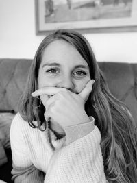 Portrait of young woman covering mouth at home