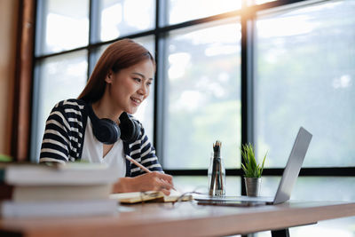 Young woman using mobile phone at table