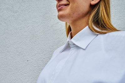 Close-up portrait of woman standing against white wall