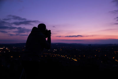 Silhouette man photographing against sky during sunset