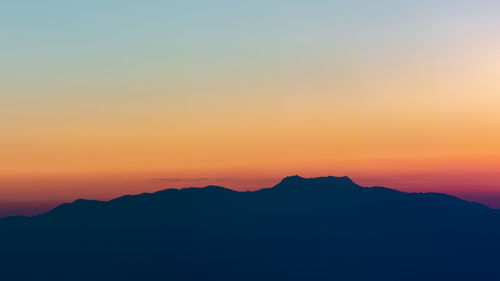 Scenic view of silhouette mountains against orange sky