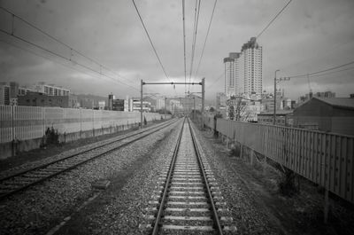 Railroad tracks in city against sky