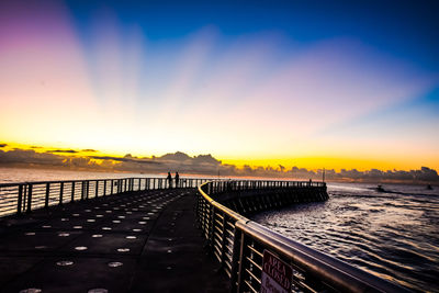 Bridge over sea against sky during sunset