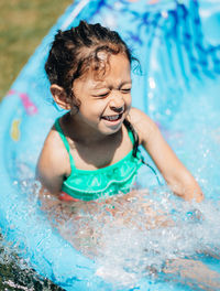 Cute smiling girl sitting in wading pool outdoors