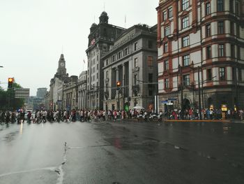 Group of people walking on wet street in city