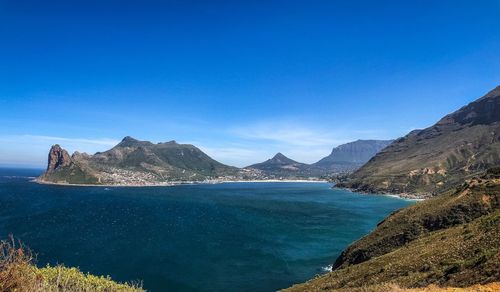 Scenic view of sea and mountains against clear blue sky