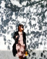 Woman with arms outstretched against trees