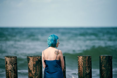 Beautiful blue-haired woman in long dark blue dress with cute tattoo on her shoulder blade