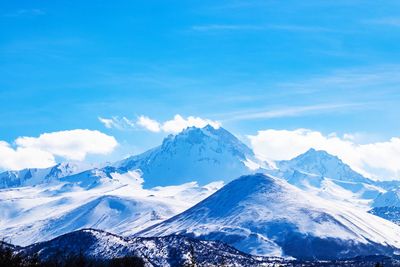 Scenic view of snowcapped mountains against blue sky