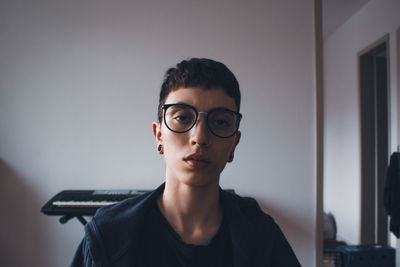 Portrait of young woman wearing sunglasses against wall