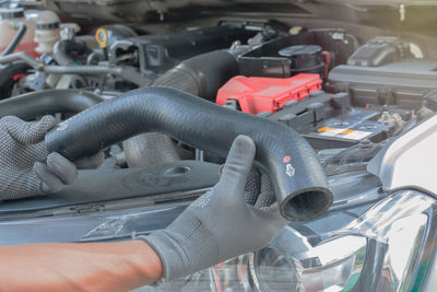 Close-up of mechanic hand holding vehicle part by car engine