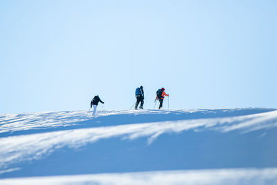 People walking on snowcapped mountain against sky