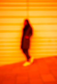 Defocused image of woman standing by wall outdoors