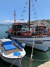 Fishing boats moored at harbor against blue sky