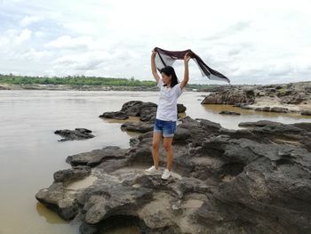 Full length of man standing on rock at beach against sky