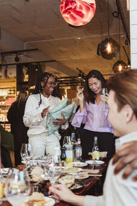 Multiracial female friends laughing while celebrating during dinner party