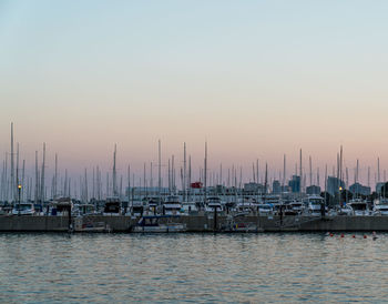 Sailboats moored in harbor against sky during sunset