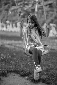 Cute girl sitting on swing at playground