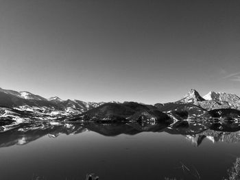 Scenic view of lake by snowcapped mountains against clear sky