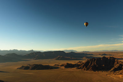 Hot air balloon flying over desert against sky