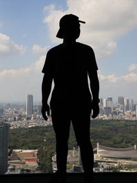 Rear view of silhouette man standing against buildings in city