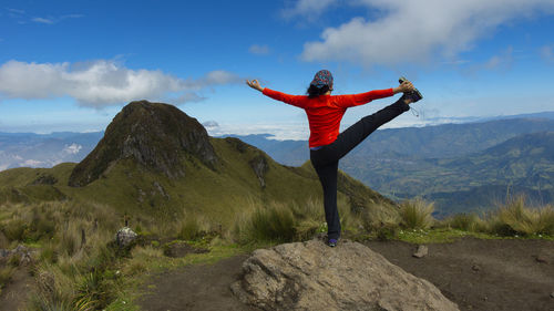 Young concentrated latin woman practicing yoga on a rock on the summit of a mountain during a day