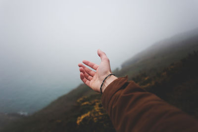 Midsection of person against mountain during foggy weather