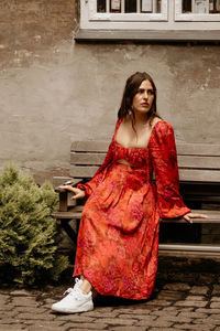 Portrait of young woman standing against wall