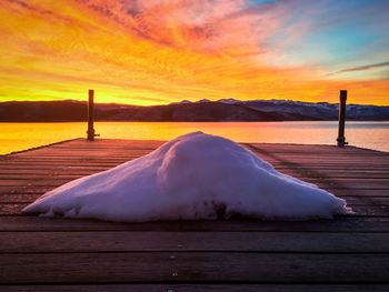 Scenic view of lake against cloudy sky during sunset